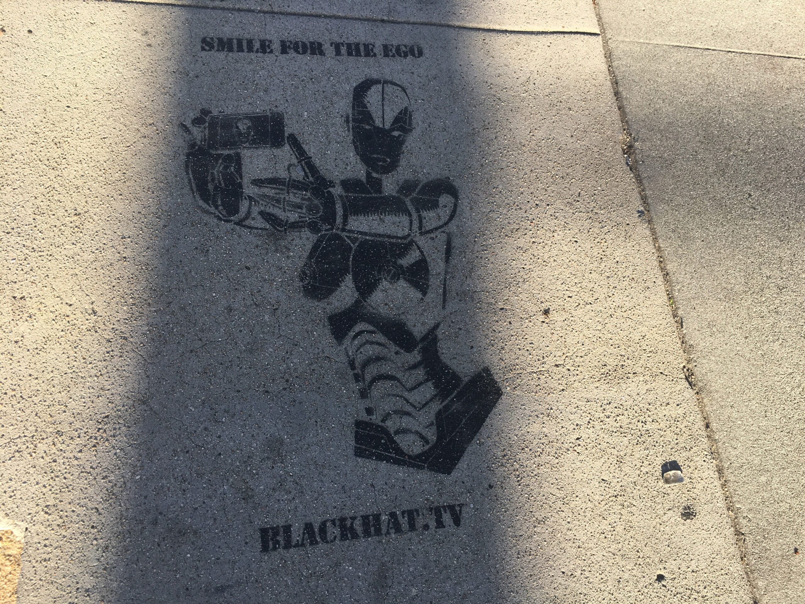 Stencil street art promoting BLACKHAT.TV on Traction Avenue sidewalk, Los Angeles, 2016